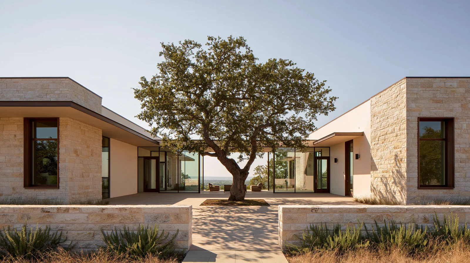 Casa in pietra chiara attorno a un grande albero