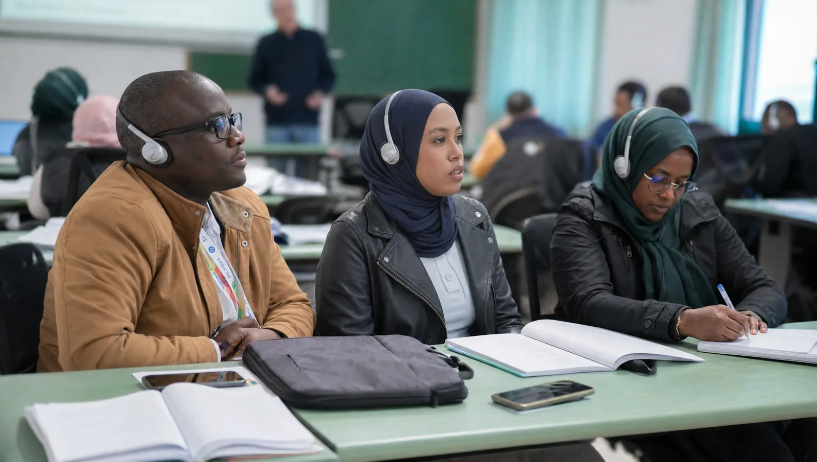Studentesse e studenti internazionali in aula, con cuffie e quaderni